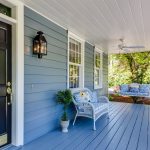 Image of a house with a blue porch and a white wicker couch and a porch swing
