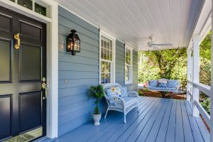 Image of a house with a blue porch and a white wicker couch and a porch swing